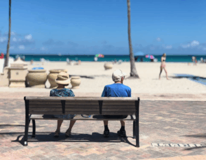 Senior man and woman sitting on beach bench (FATJOE only)