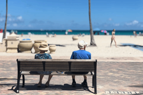 Senior man and woman sitting on beach bench (FATJOE only)