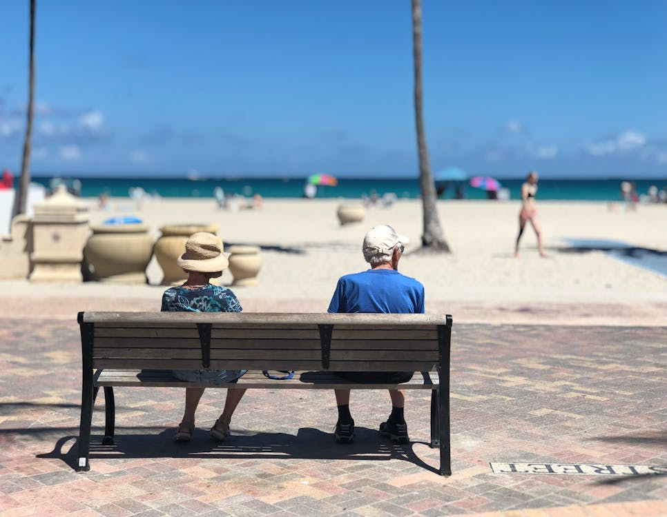 Senior man and woman sitting on beach bench (FATJOE only)