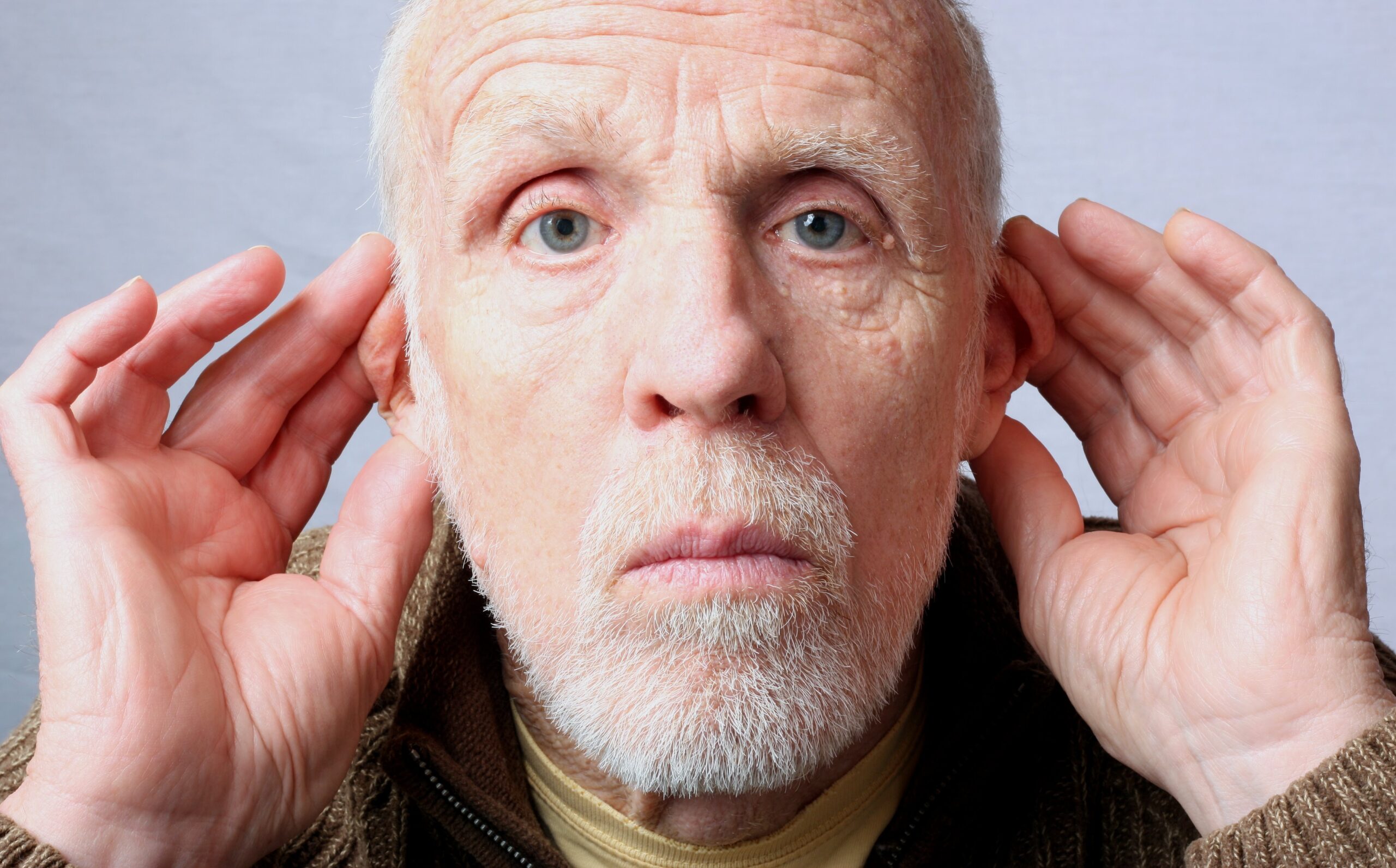 Hearing-impaired senior man ttyring to listen
